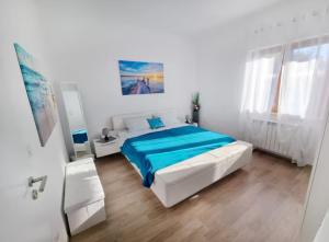 - une chambre blanche avec un lit et une couverture bleue dans l'établissement App Meri, à Savudrija
