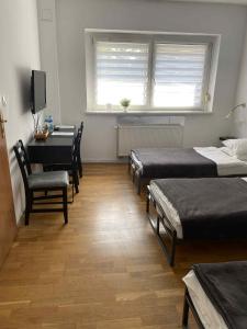 Pokój z 3 łóżkami, stołem i biurkiem w obiekcie Nest Nocleg Poznań w Poznaniu