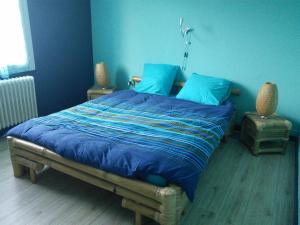 a bedroom with a large bed with blue sheets at La Maison Du Lavoir in Payroux