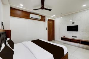 a bedroom with a bed and a flat screen tv at Hotel O Shubh Sankalp in Ahmedabad