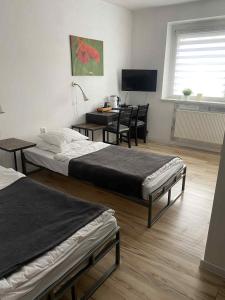 sypialnia z 2 łóżkami, stołem i biurkiem w obiekcie Nest Nocleg Poznań w Poznaniu
