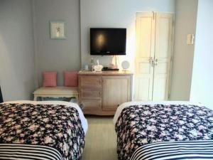 a hotel room with two beds and a tv at Baan Hmon-Oon in Chiang Mai