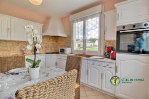 a kitchen with white cabinets and a table with chairs at Ty lann in Pluvigner