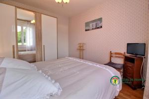 a bedroom with a white bed and a tv at Ty lann in Pluvigner