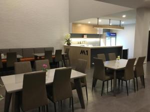 a dining room with tables and chairs and a kitchen at M-one Residence in Ban Kohong