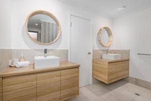 a bathroom with two sinks and two mirrors at Vogue Design Footpath to the beach in Busselton +26 photos