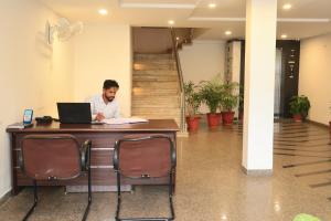 a man sitting at a desk with a laptop at Hotel Future Inn in Bhopal