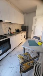 a kitchen with white cabinets and a table and a stove at Studio Alice Mia in Chiajna +3 photos