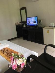 a room with a bed with a television and flowers at Ban Noi Resort Phrae in Sop Sai