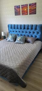 ein großes Bett mit blauem Kopfteil in einem Schlafzimmer in der Unterkunft Apartamentai AGNIJA in Kretinga