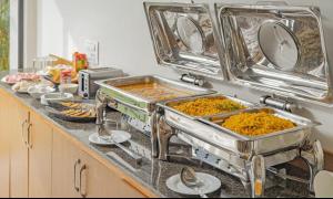a kitchen counter with trays of food on it at The Embassy Inn - Sector 20 Noida in Noida