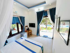 a bedroom with a bed with blue curtains and windows at Villa Sapphire in Vung Tau +142 photos