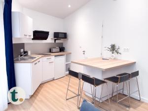 a kitchen with white cabinets and a counter with stools at Tranquiloue - Petite Maison à 10 min du PuyduFou in Les Herbiers +5 photos