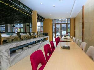 LiboにあるLavande Hotels·Qiannan Liboの長テーブルと赤い椅子が備わるレストラン