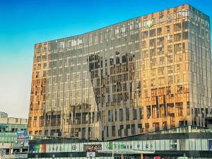 un grand bâtiment en verre avec beaucoup de fenêtres dans l'établissement Gtel Rock City Qingdao Hotel, à Laoshan