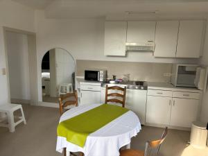 a kitchen with white cabinets and a table and chairs at Petite chatelaine in Herbeumont +5 photos