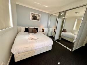 a bedroom with a large white bed and a mirror at Modern 2-Bedroom Apartment 7mins to Paramatta Train Station in Sydney