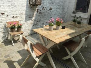 a wooden table and chairs with potted plants on it at ieperlee 23 Holiday Home in Ieper