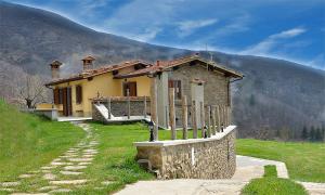 a small house on a hill in front of a mountain at Agriturismo Prato Fiorito in Bagni di Lucca