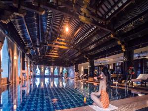 a woman sitting on the edge of a swimming pool at Tong Que Tai Jinling Hotel Tongling Anhui in Tongling