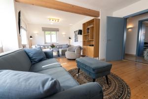 a living room with a blue couch and a chair at Landhaus Paco Ferienhaus für 12 Personen mit Alpakas, Sauna & Kamin in Blaufelden +24 photos