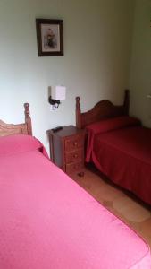 two beds in a bedroom with pink sheets and a table at Hidalgo in Alcaudete