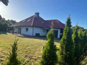 a white house with a red roof and some trees at Sands Dom Szteklin in Szteklin
