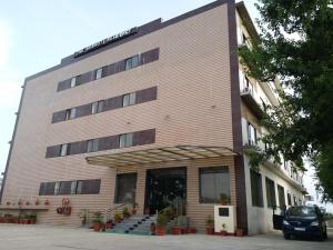 un gran edificio de ladrillo con un coche aparcado delante de él en Hotel Sravasti Residency, en Katra