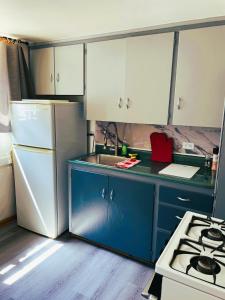 a kitchen with blue cabinets and a white refrigerator at Cabernet Sauvignon Escape in Calgary