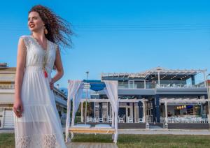 a woman in a white dress standing in front of a building at Must Boutique Hotel & Restaurant in Kanali