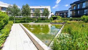 ogród ze stawem przed budynkiem w obiekcie Prestige Apartments Botanica w Gdańsku