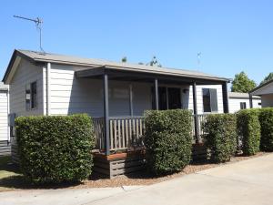 a white house with bushes in front of it at Dalby Tourist Park in Dalby