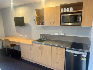 a kitchen with a counter and a sink and a microwave at Pokeno Motel in Pokeno