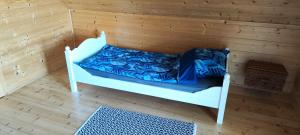 a white bed in a room with a wooden wall at Przy jeziorze in Kaliska Kośierskie