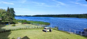 a white van parked on a field next to a lake at Przy jeziorze in Kaliska Kośierskie
