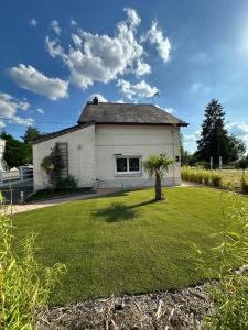 a white house with a palm tree in the yard at Le petit Nid du Solrezis in Solre-le-Château
