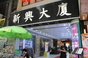 a person standing in front of a store with a green umbrella at New Star Guest House in Hong Kong