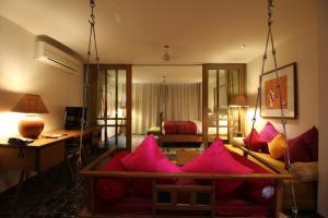 The Sky Imperial Aarivaa Luxury HomeStay في راجكوت: غرفة معيشة مع وسائد وردية على أريكة