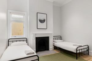 two beds in a room with a fireplace at Bath Street Cottages in Adelaide