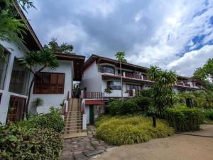 a house with palm trees in front of it at Waterford Valley Chiangrai Golf Course and Resort in Chiang Rai