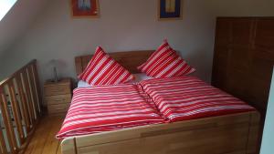 uma cama com almofadas listradas vermelhas e brancas em Haus Oltmanns em Quanens