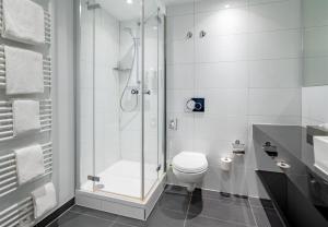 a white bathroom with a shower and a toilet at Spark by Hilton Wuppertal City Centre in Wuppertal