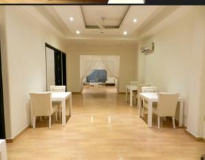 a dining room with white tables and chairs and a couch at The G8 in Noida +16 photos