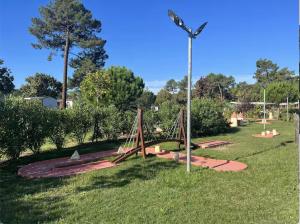 einen Spielplatz in einem Park mit Schaukel in der Unterkunft Douce Escale in Lège-Cap-Ferret