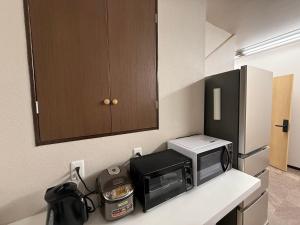 a kitchen with a microwave and a toaster oven on a counter at ゲストハウスシナノスイー Guest House Shinano Swee in Omachi