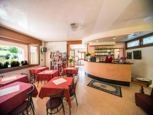 un restaurante con mesas rojas y una mujer detrás del mostrador en Albergo Centrale, en San Zeno di Montagna