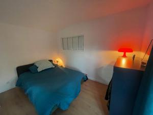 1 dormitorio con cama azul y lámpara roja en L'ancrage, en Sotteville-sur-Mer