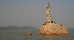 a rock with a statue on it in the water at Downtown Hotel in Zhuhai