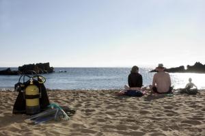 grupa trzech osób siedzących na plaży w obiekcie Apartamentos Guanarama w Puerto del Carmen
