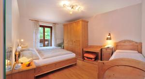 a bedroom with two beds and a desk and a window at Residence Hofer in Bressanone